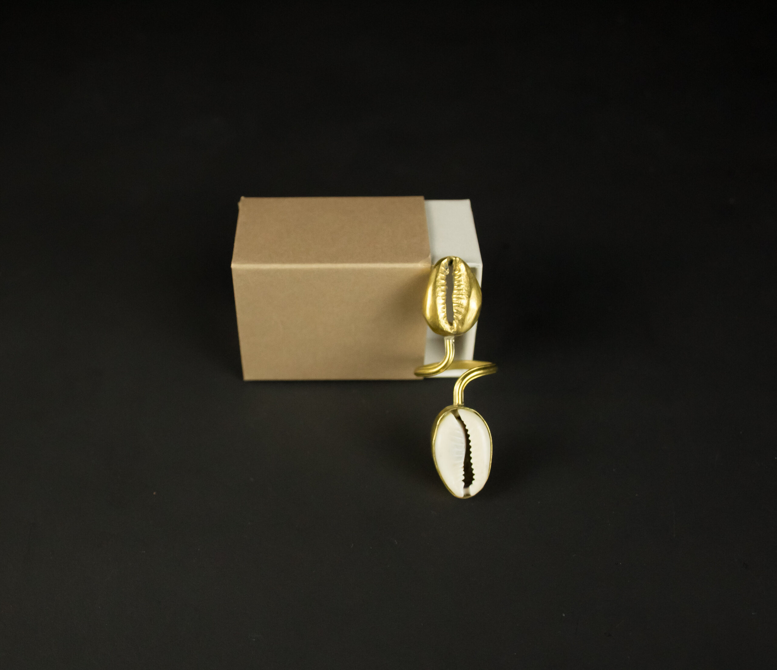 Bague Jojo Création avec un cauri doré et un cauri naturel présentée dans son écrin cadeau festif.