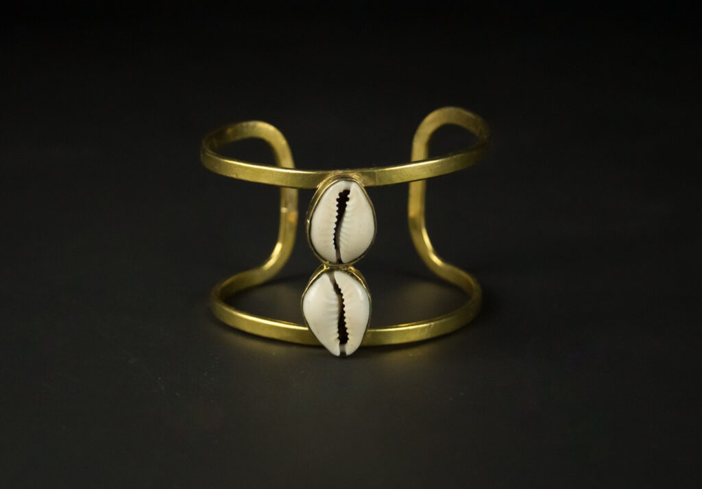 Bracelet en métal doré orné de deux cauris et motif main - Modèle La Main Magique par Jojo Création.