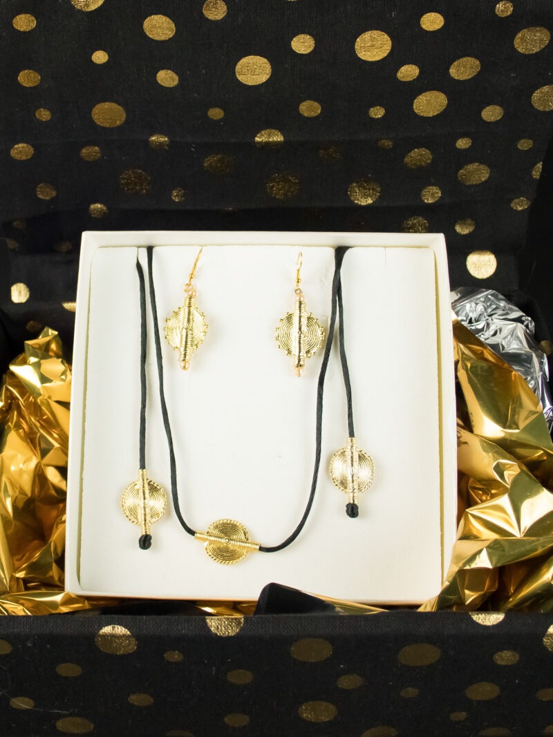 Coffret cadeau Jojo Création Poids Akan Soleil : parure de bijoux dorés circulaires dans une boîte noire à pois dorés.